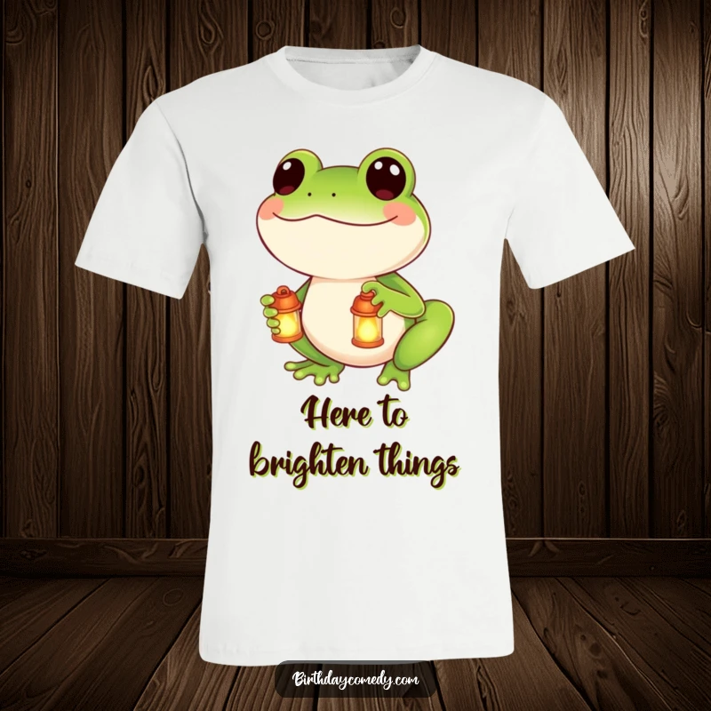Funny t-shirt showcasing a smiling frog holding a tiny, radiant lantern, adding a touch of magic and cheer.